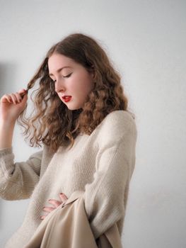 Fashion portrait of a woman in sweater posing indoors with a winter vibe.