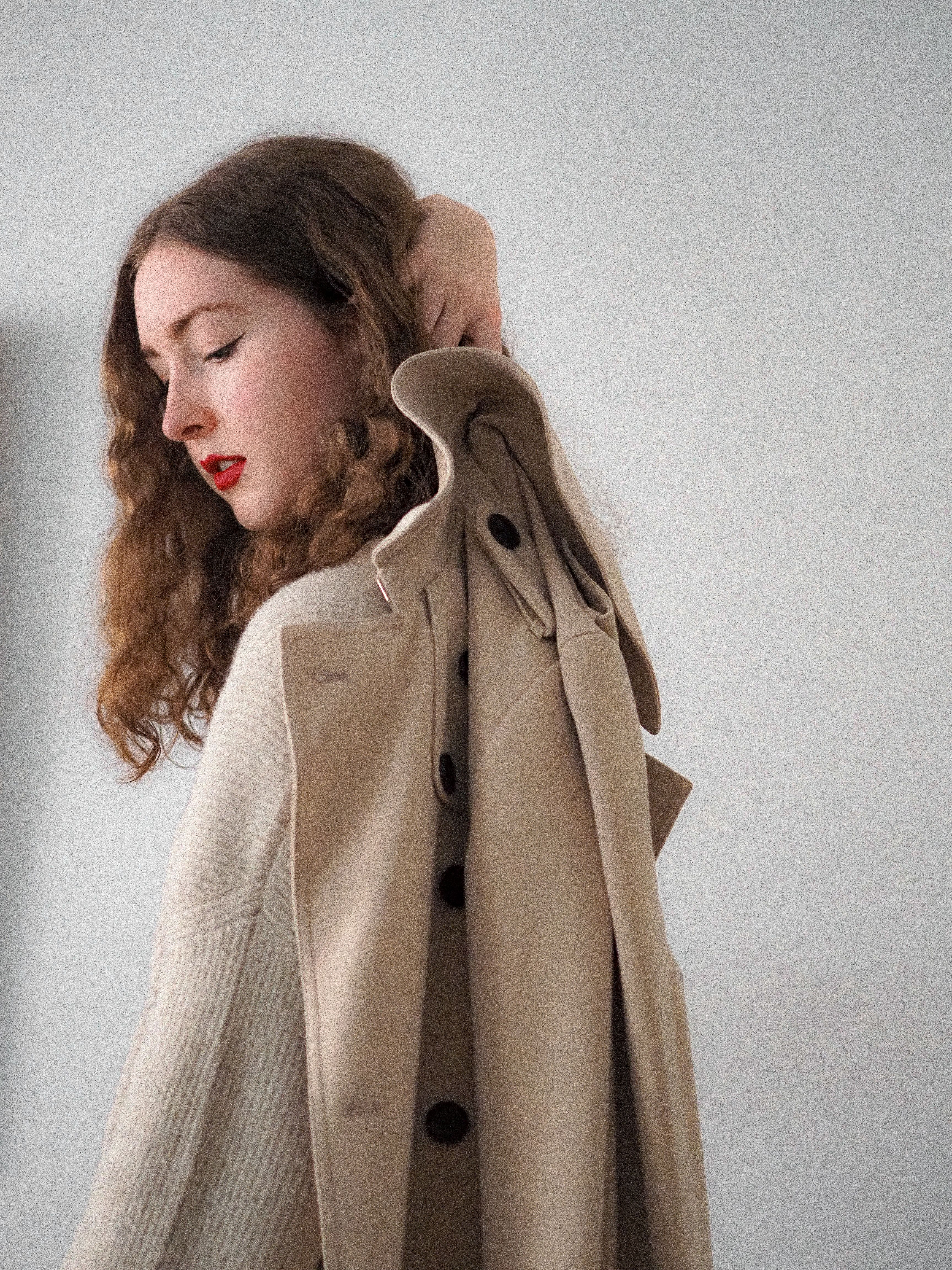 A woman is wearing a trench coat · Free Stock Photo