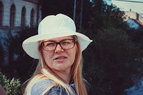 免费 在白色的太阳帽和眼镜的雀斑女人的特写照片 素材图片