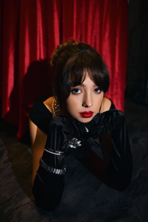 Free Portrait of elegant woman with red lips wearing gloves and pearls in a luxurious setting. Stock Photo