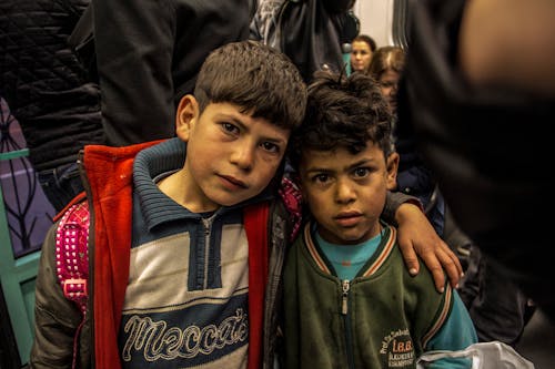 Two boys are standing together in a crowded area