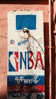 Graffiti-covered wall with a street basketball hoop, showcasing urban art style.