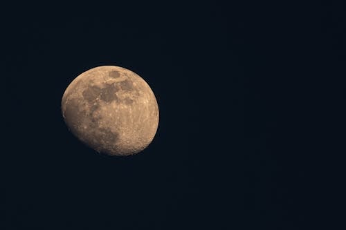 A full moon is seen in the dark sky