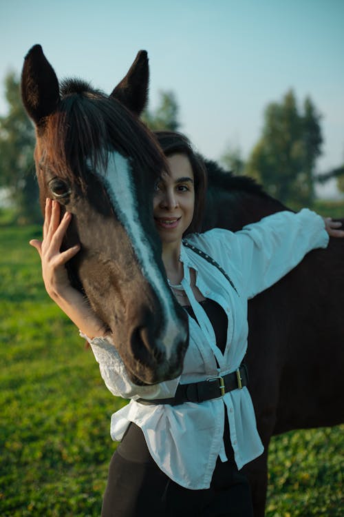A woman is holding a horse in a field
