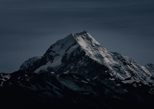 Majestic snow-covered peak in New Zealand captured at night, showcasing its striking silhouette.