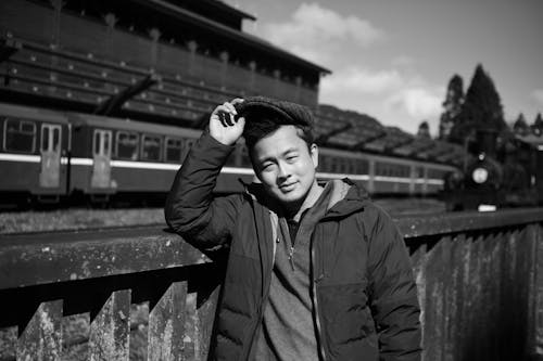 A man in a jacket leaning against a fence