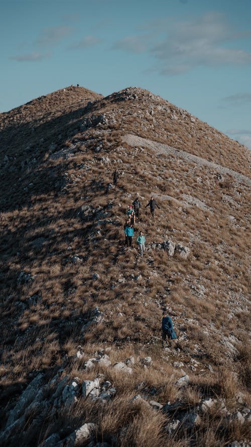People hiking up a hill with a blue sky