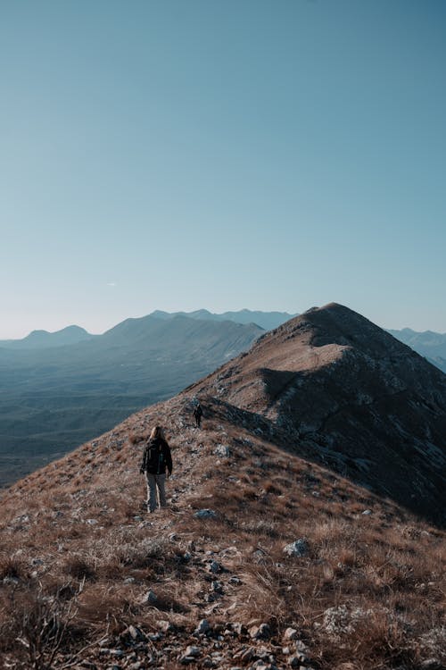 A person walking up a mountain with a blue sky
