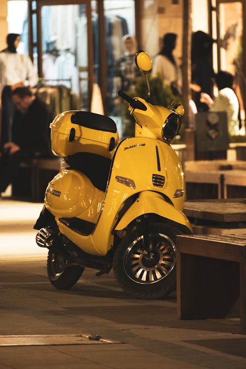 A yellow moped parked in front of a store