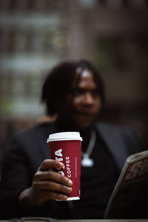 A man holding a coffee cup and newspaper