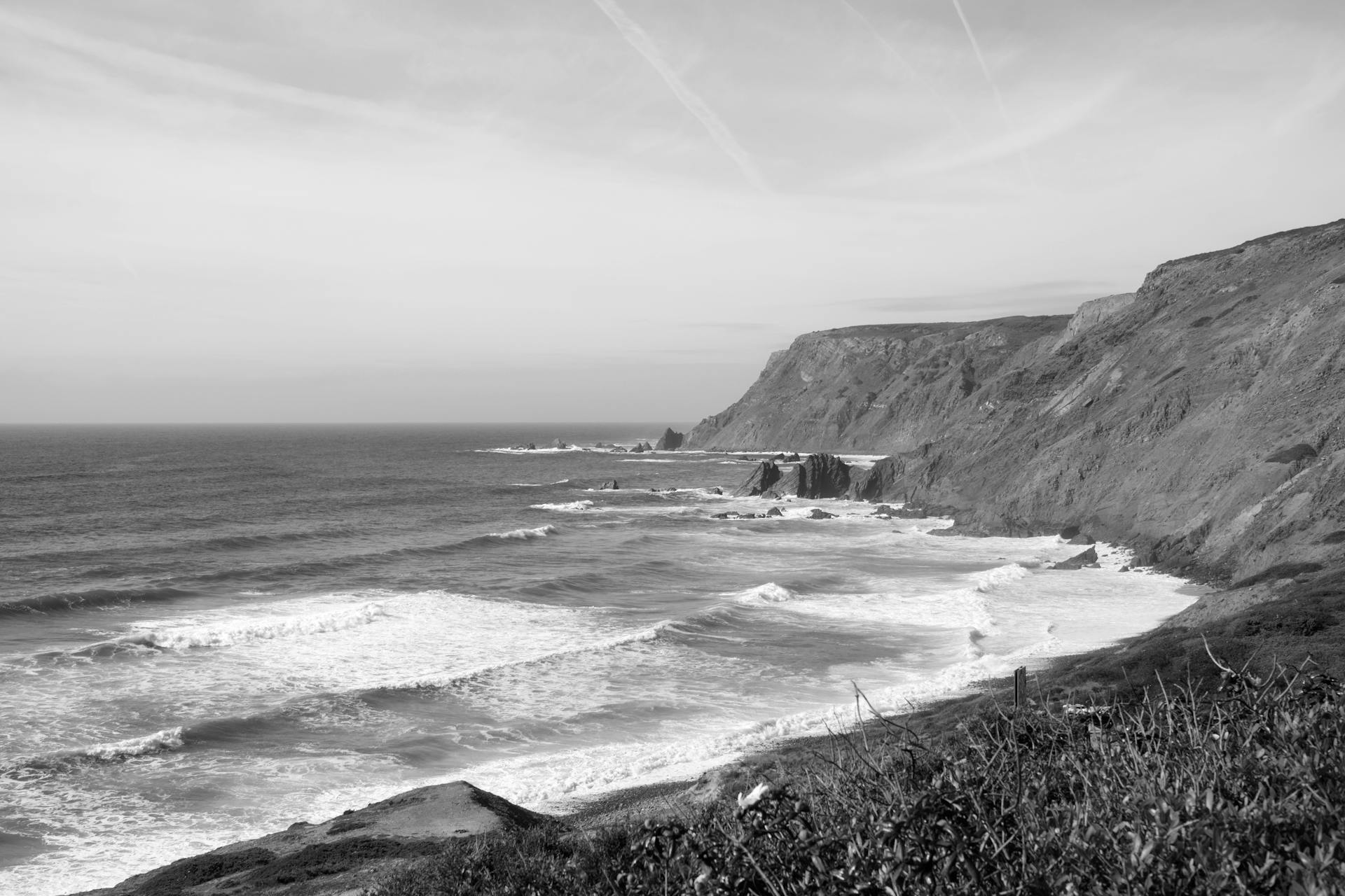 Stunning black and white photograph of the Algarve coastline in Portugal featuring dramatic sea cliffs.