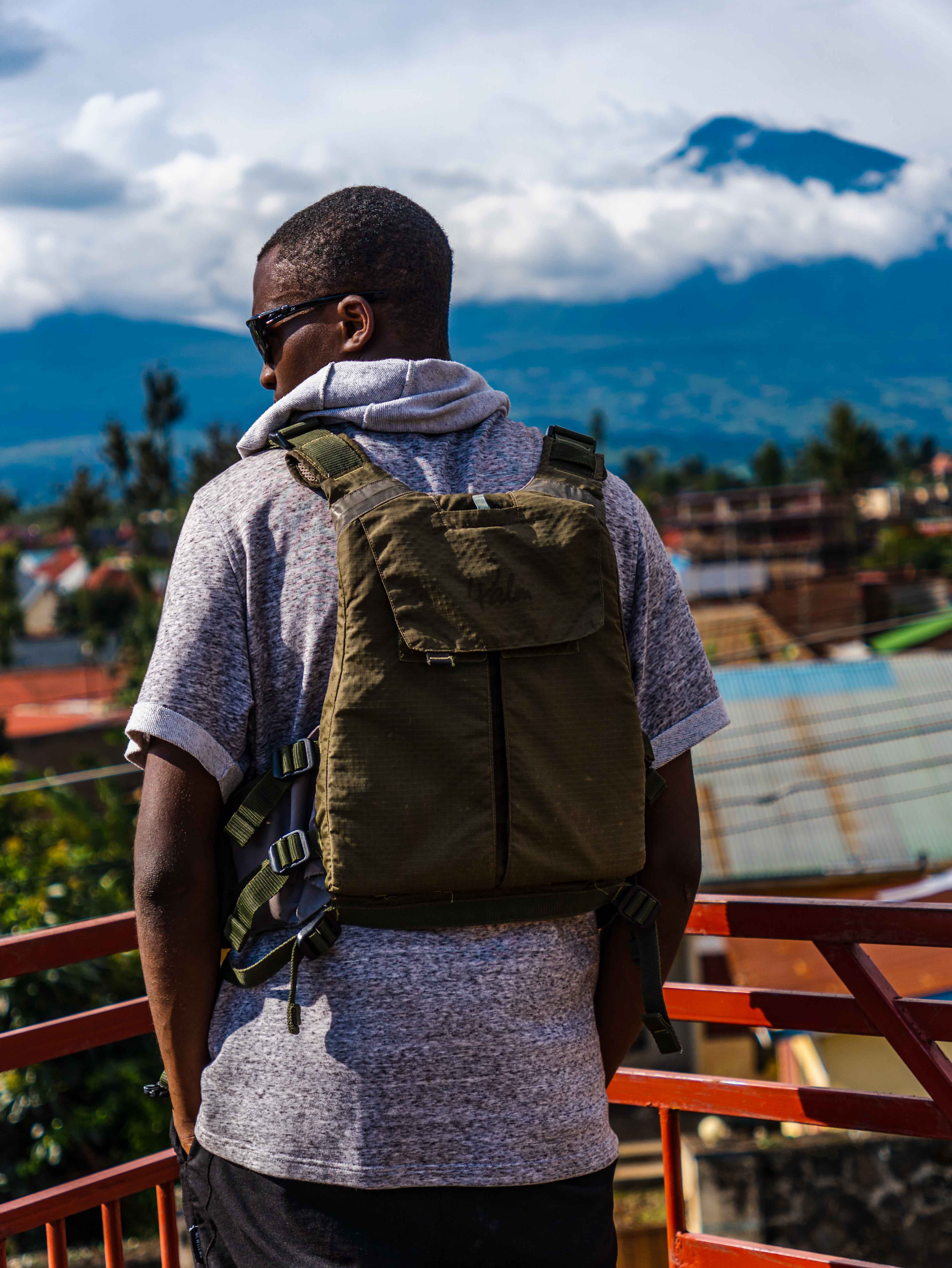 Man with backpack gazing at mountains from a terrace on a sunny day.