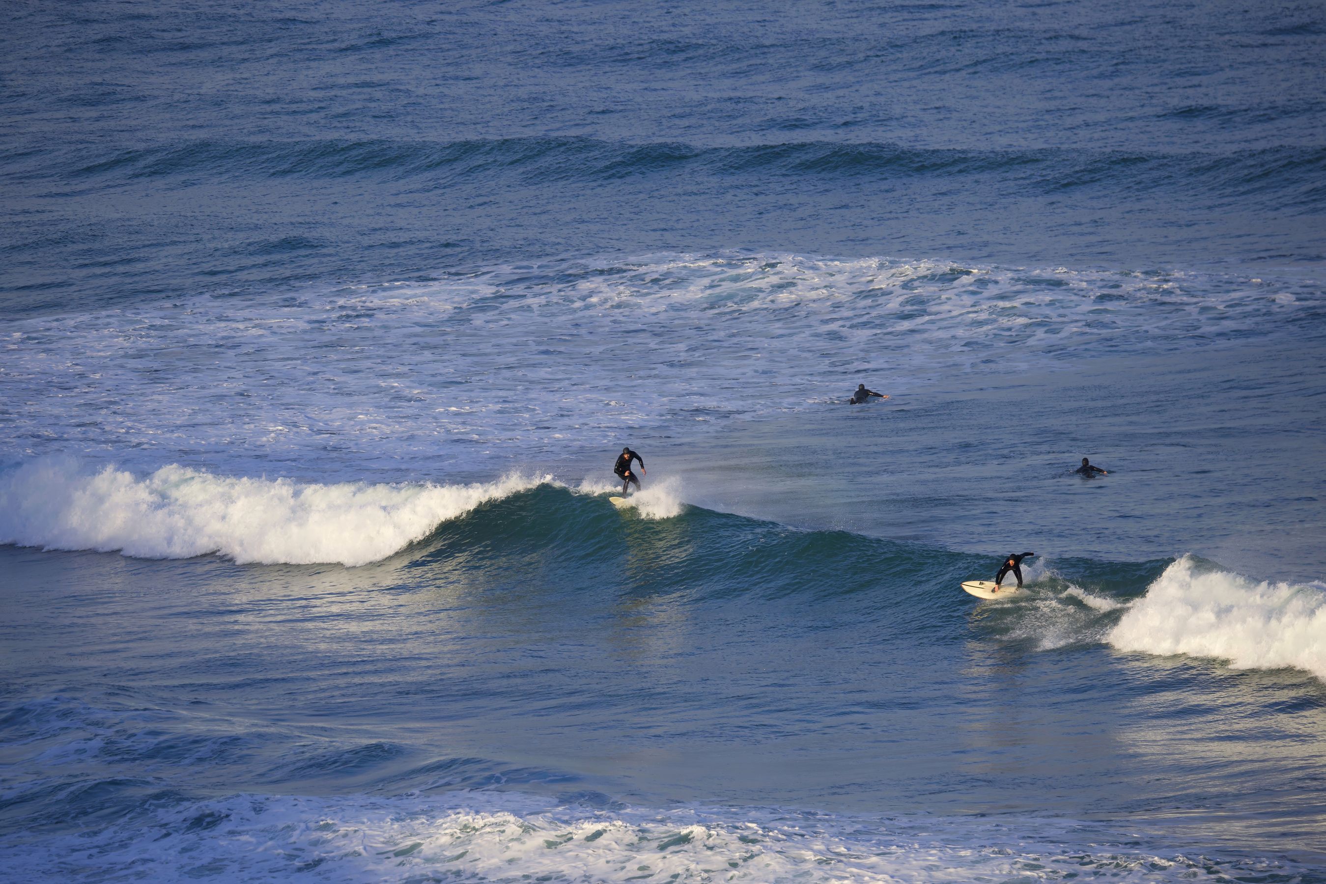 Surfers riding waves at Watergate Bay, Cornwall