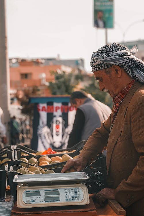 A man in a turban is weighing fruit