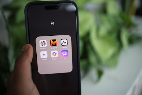 A person holding an iphone with the app icons on it