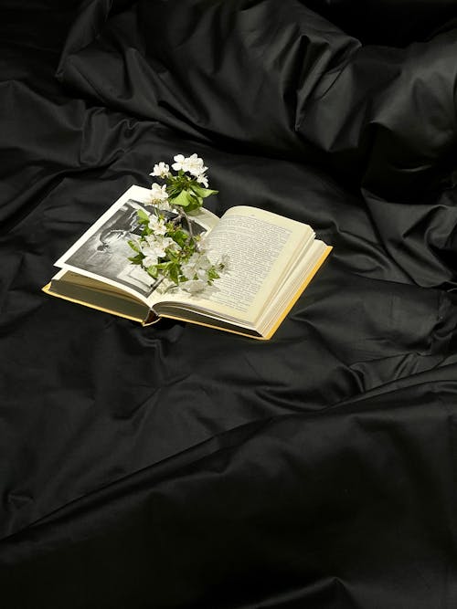 A book with flowers on it sitting on top of a black sheet