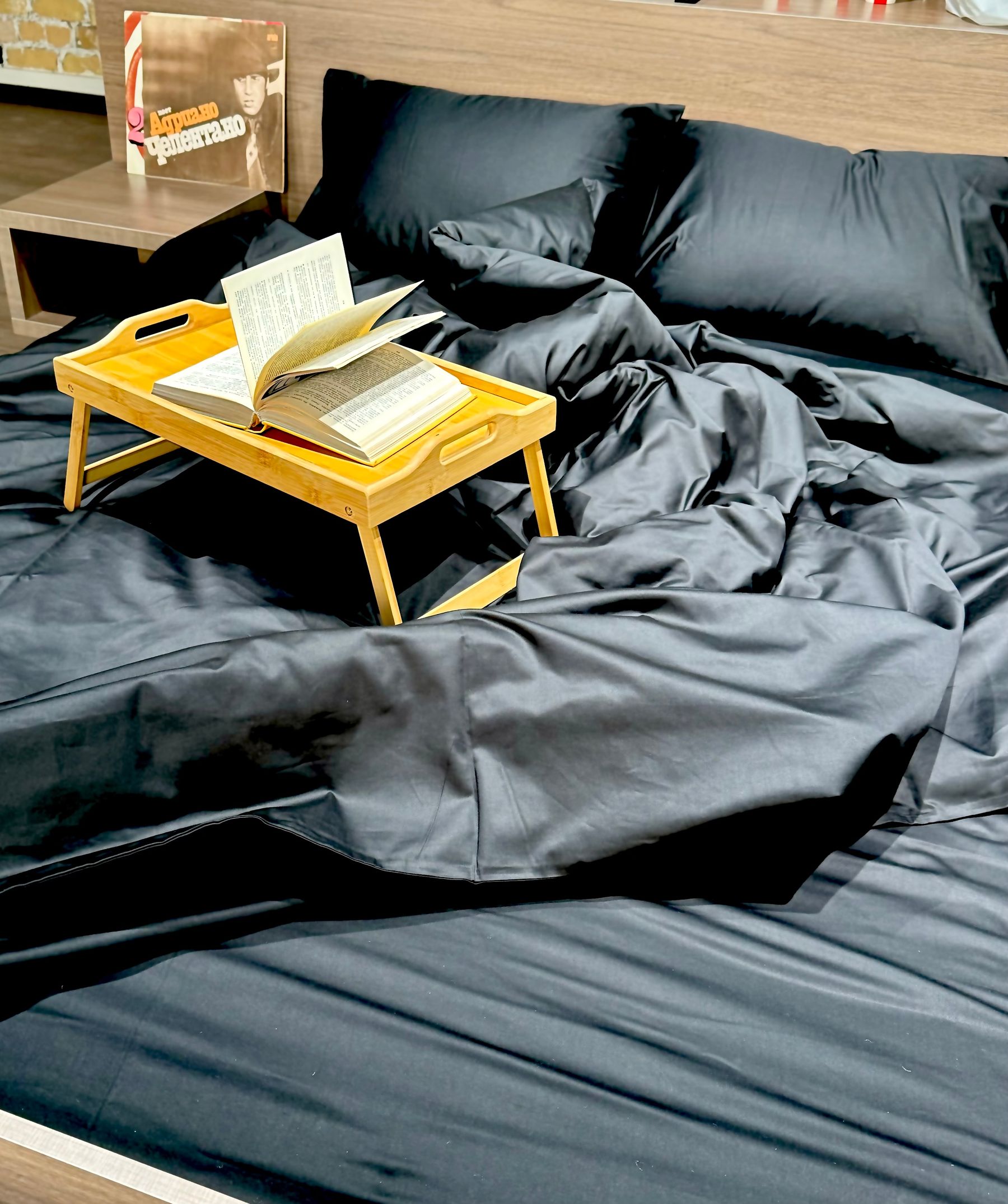 Close view of black bedding with books and a warm wooden tray