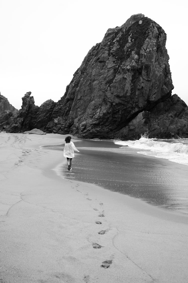 Woman Walking On Beach To Rock