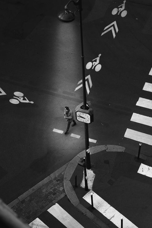 Free Black and white aerial photo of a city crosswalk with a lone pedestrian at night. Stock Photo
