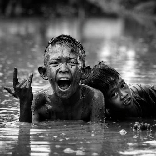 Two boys in the water with their hands up