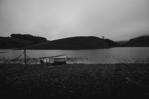 A boat is sitting on the shore of a lake