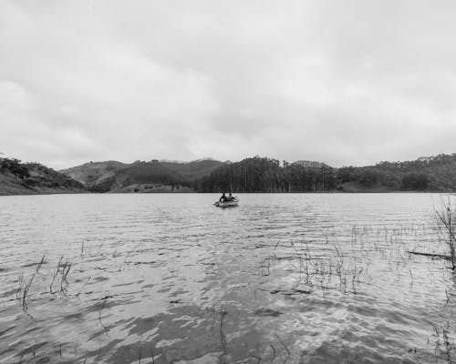 A black and white photo of a man in a canoe on a lake