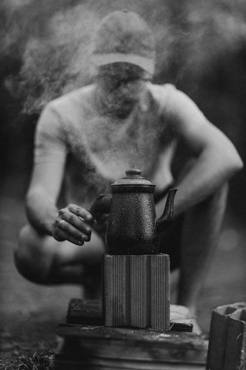 A man is sitting on a bench with a kettle