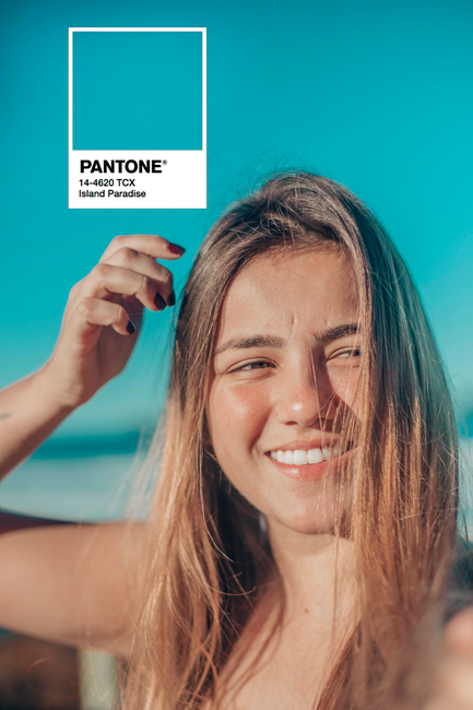A cheerful young woman enjoys a sunny day with a vibrant blue sky as the backdrop.