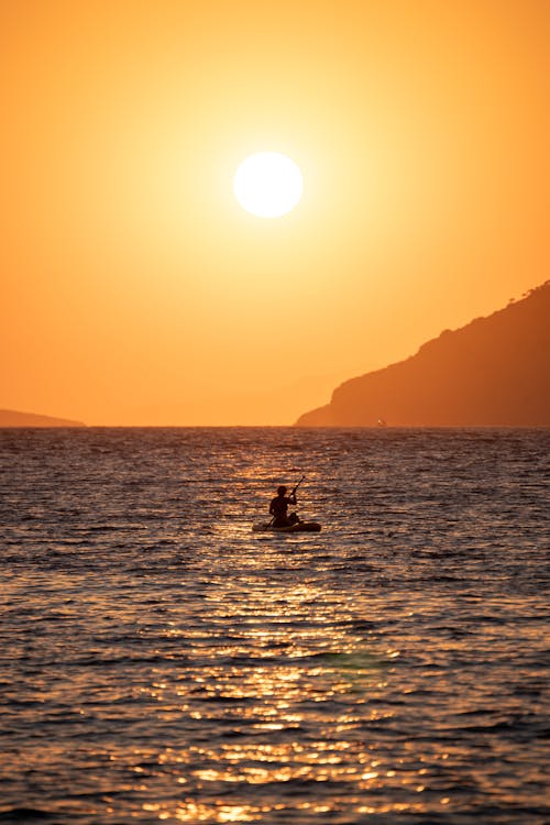 Free Person on Raft on Calm Sea at Sunset Stock Photo