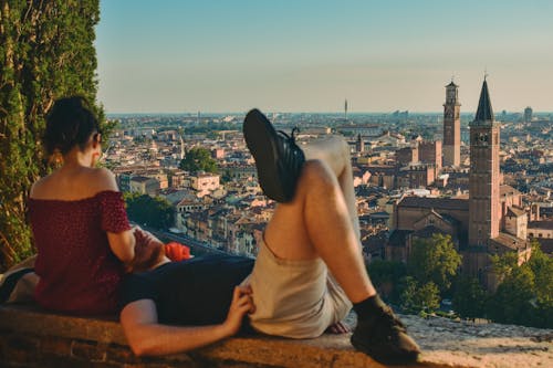 A couple sitting on a ledge overlooking a city