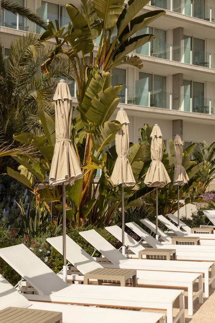 Relaxing poolside view at a Calafell resort hotel, featuring sunbeds and lush greenery.