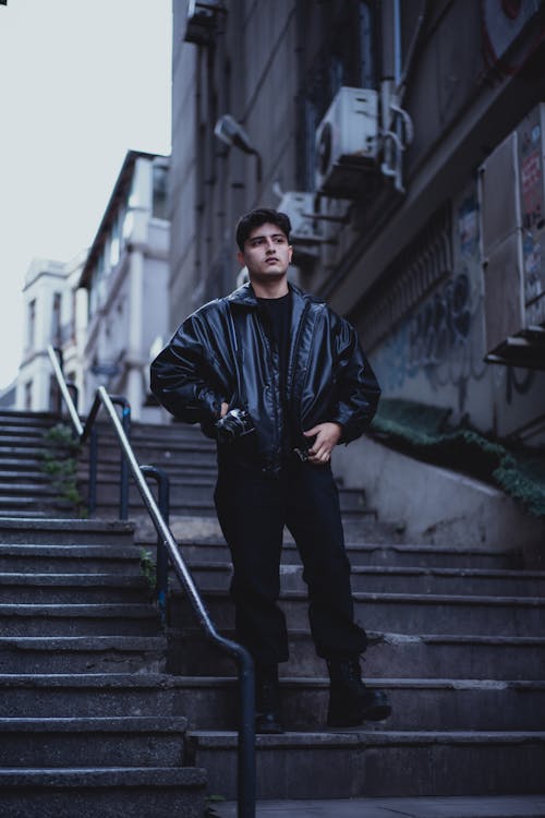 A man in black leather jacket standing on some stairs