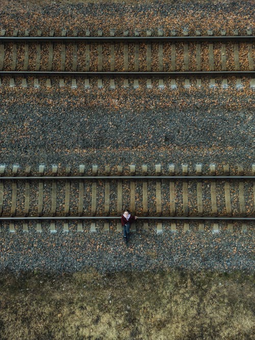 A person standing on the tracks of a railroad