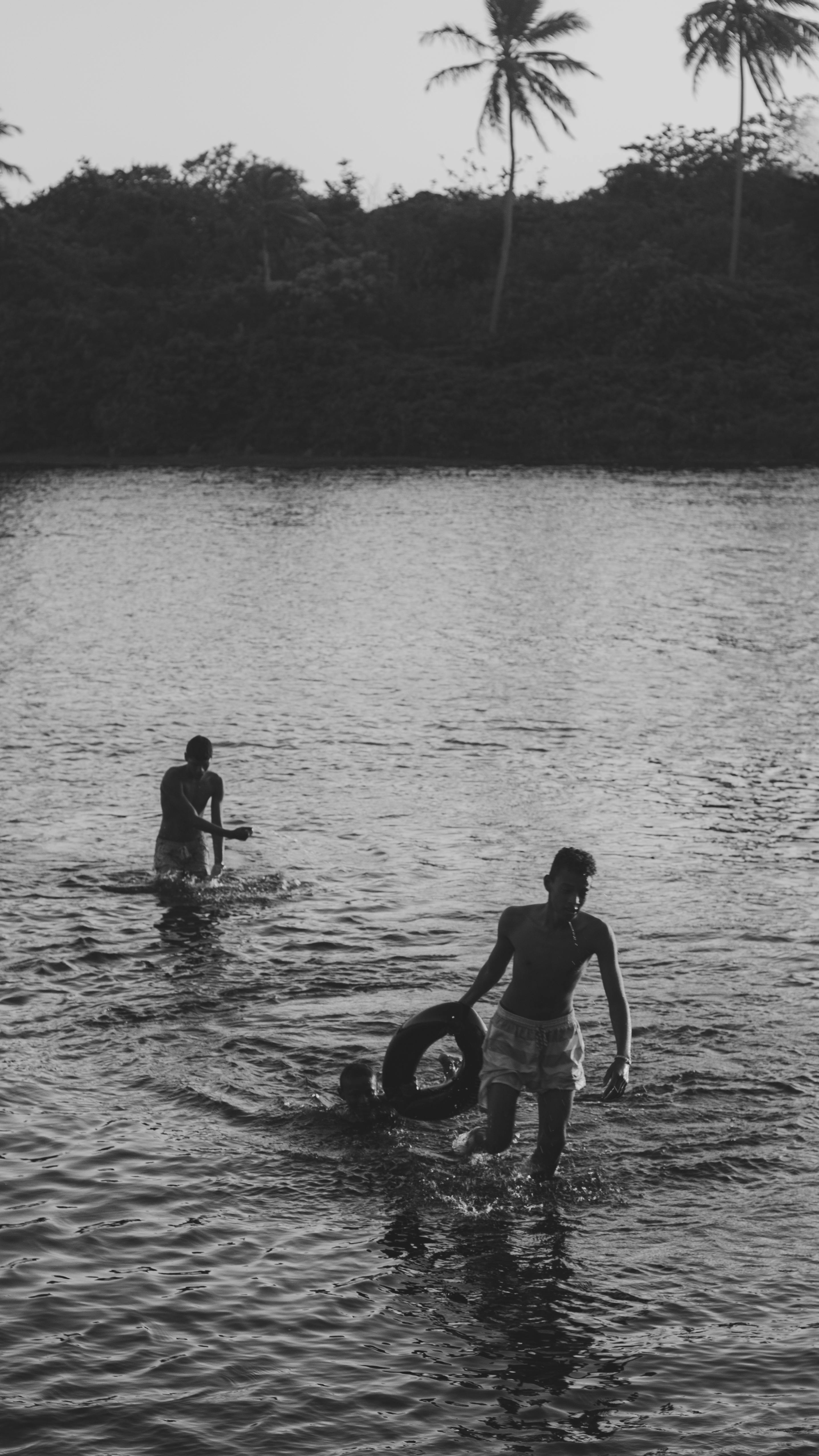 Black and white photo of teenagers swimming and playing in a lake during summer.