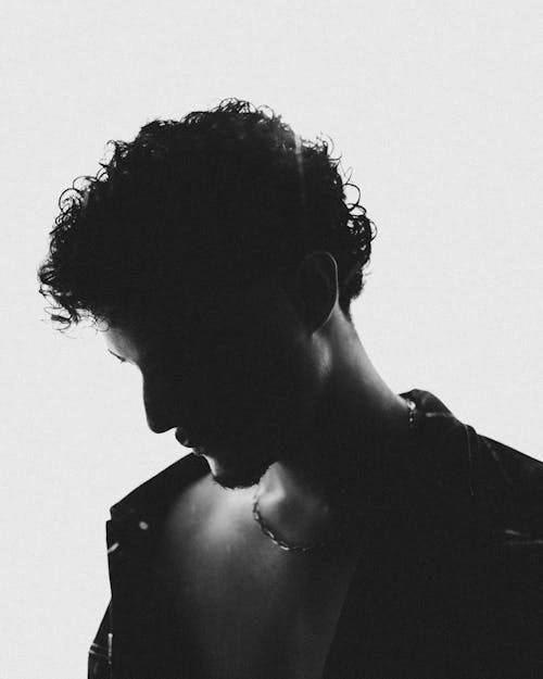 Free Silhouette portrait of a young man in black and white, creating a dramatic mood. Stock Photo