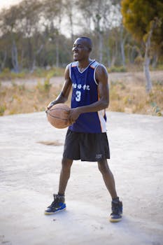 Man playing basketball on an outdoor court in Lafia, Nigeria, wearing a blue jersey.