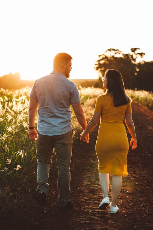 Free Couple holding hands and walking on a rural path during a beautiful summer sunset. Stock Photo