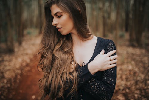 Young Woman with Long Hair Posing in a Forest in Autumn 