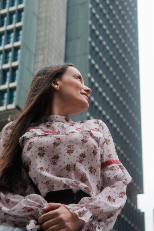 Free A young woman smiling upward against the skyscraper backdrop of São Paulo. Stock Photo