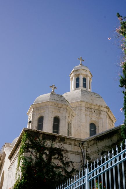 Low angle view of a historic church building with domes and crosses against a blue sky.