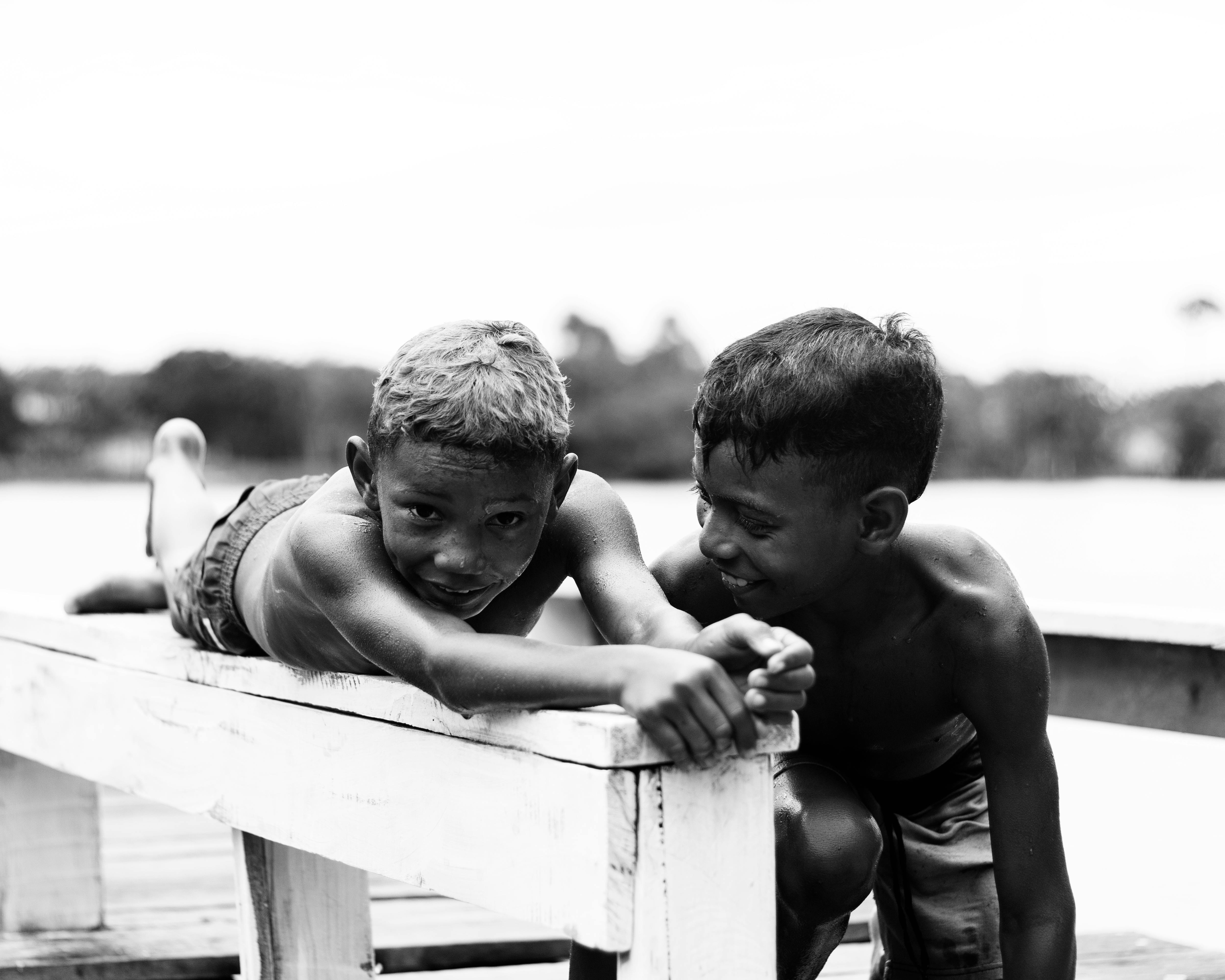 Two boys enjoying playtime on a pier in Mãe do Rio, Brazil, in a candid black and white photo.