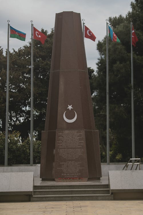 A monument with flags on it in front of trees