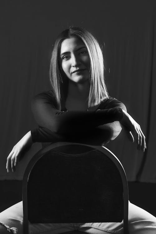 A woman sitting on a chair in black and white