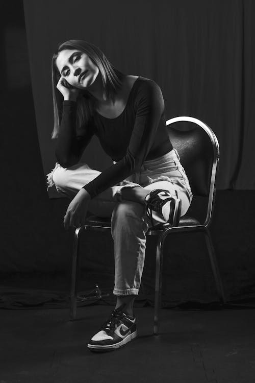 A woman sitting on a chair in black and white