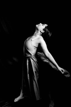 Graceful ballerina striking a pose in a black and white artistic photograph.