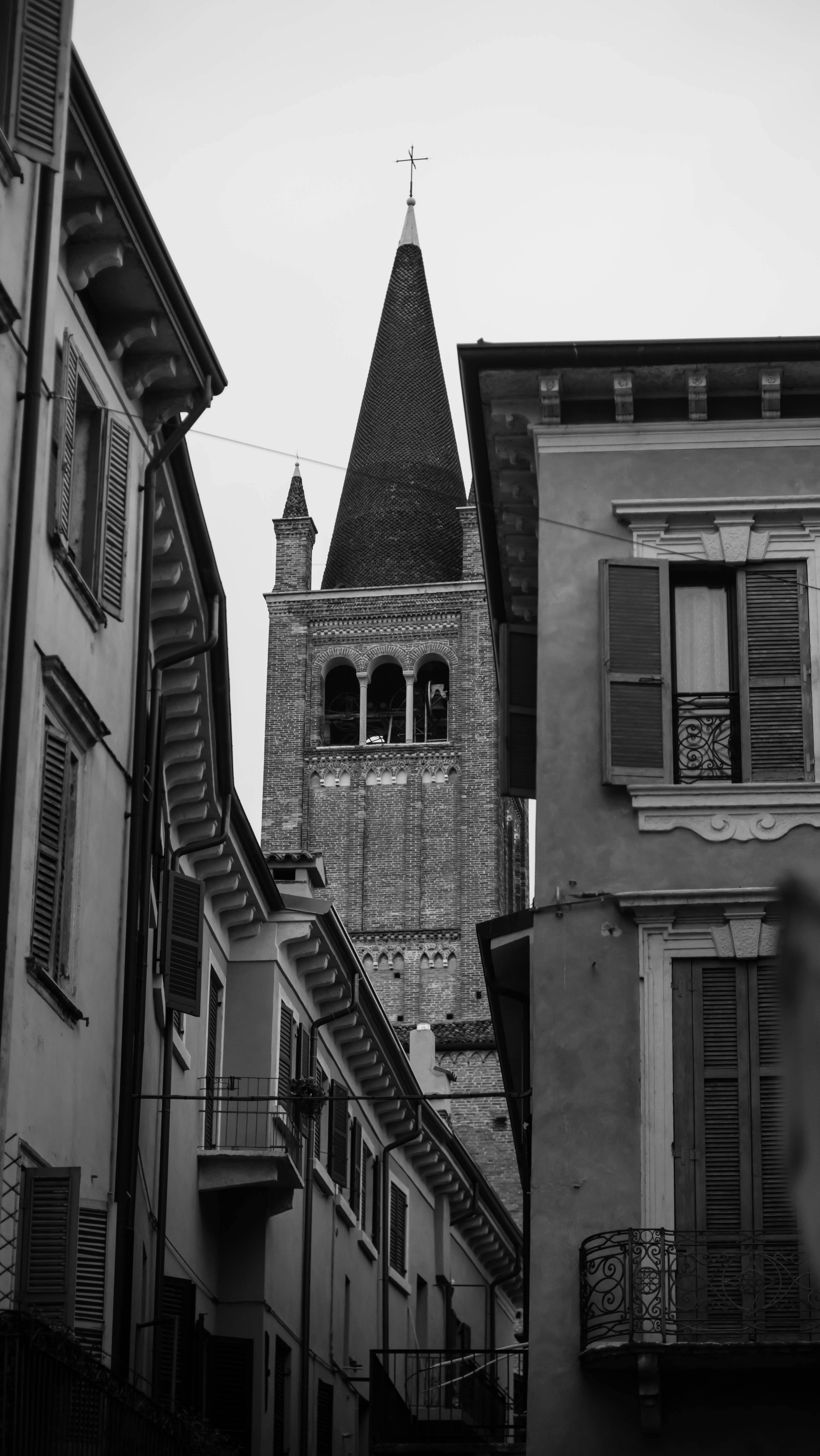 Black and white photo showcasing a gothic church tower framed by urban buildings, capturing architectural contrast.