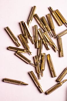 Detailed view of golden drill bits scattered over a white background, perfect for DIY and industry themes.