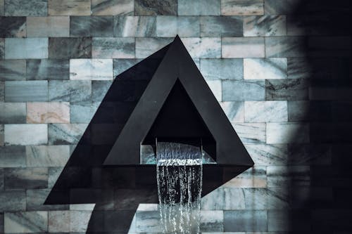 A black triangle shaped wall mounted water fountain