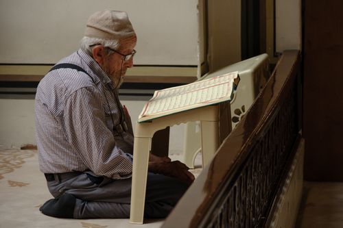 Free Elderly man kneeling and reading Quran in a mosque in Istanbul. Stock Photo