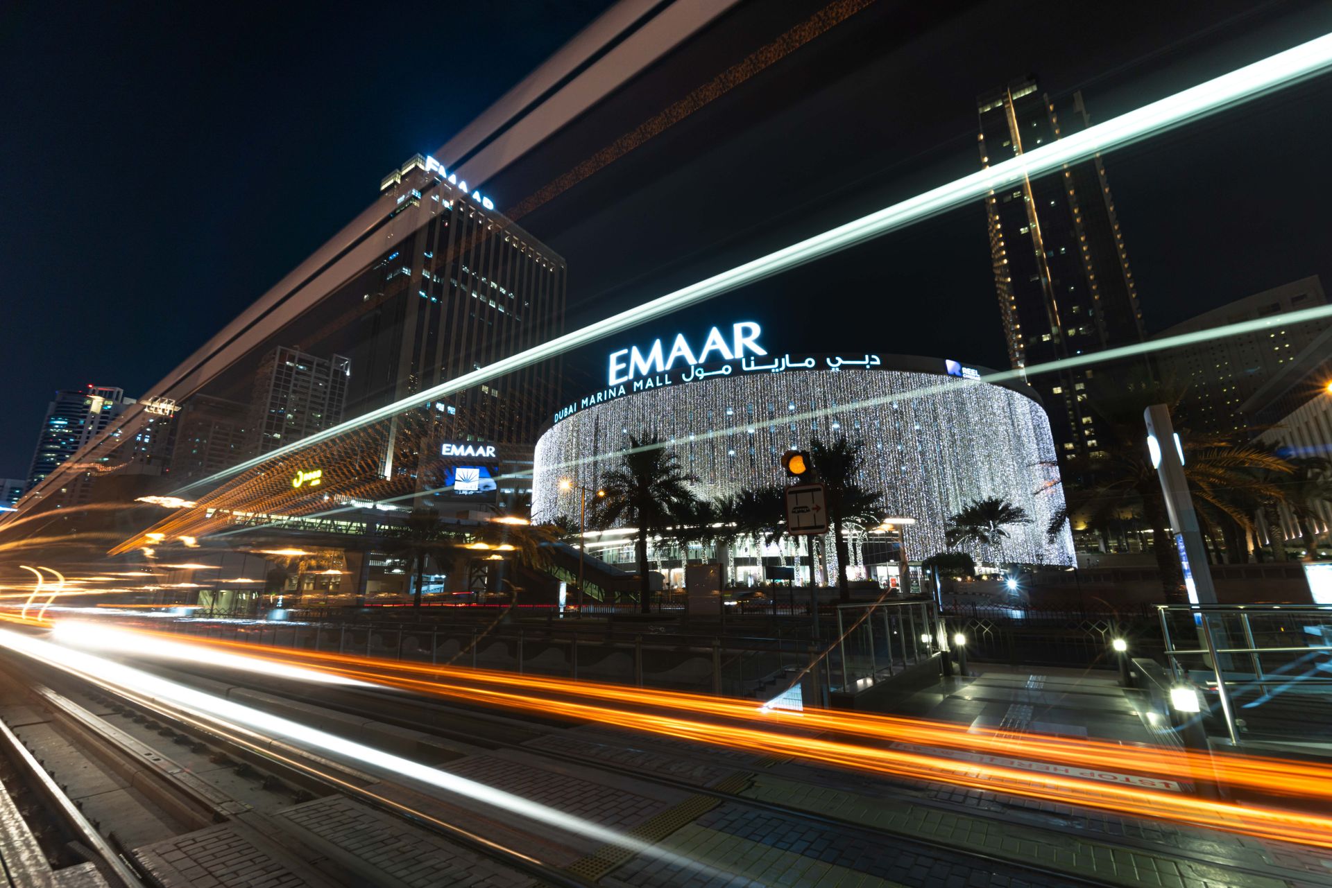 Night view of Dubai Marina Mall with dynamic light trails creating a vibrant urban scene.